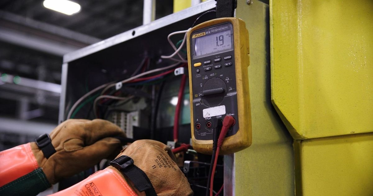 Technicien vérifie un circuit électrique avec un multimètre dans un environnement industriel
