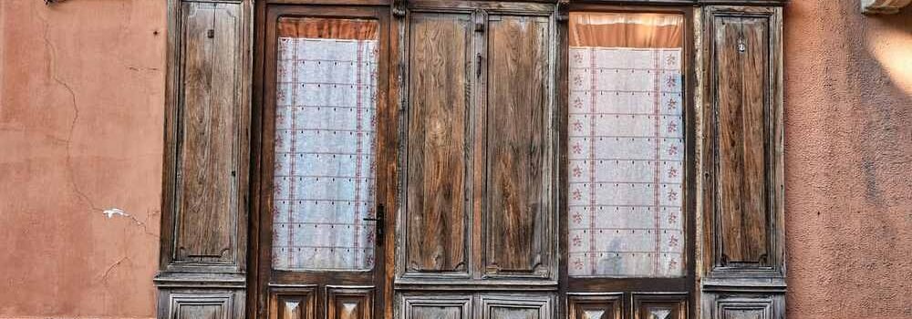 Ancienne porte en bois avec vitraux, mur terne, marches en pierre