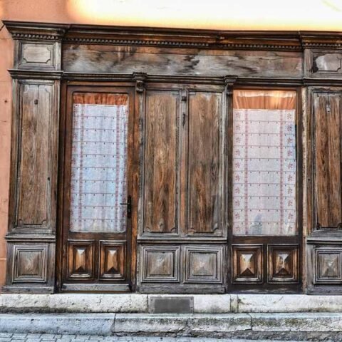 Ancienne porte en bois avec vitraux, mur terne, marches en pierre