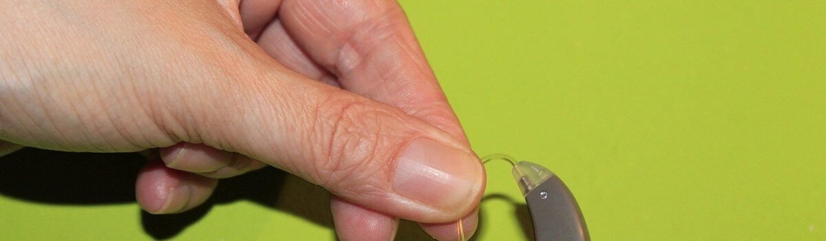 Une main tient un appareil auditif et un embout auriculaire