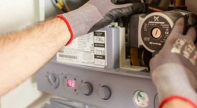 Technicien chauffagiste réglant les instruments d'une chaudière lors d'une intervention de maintenance à Toulouse
