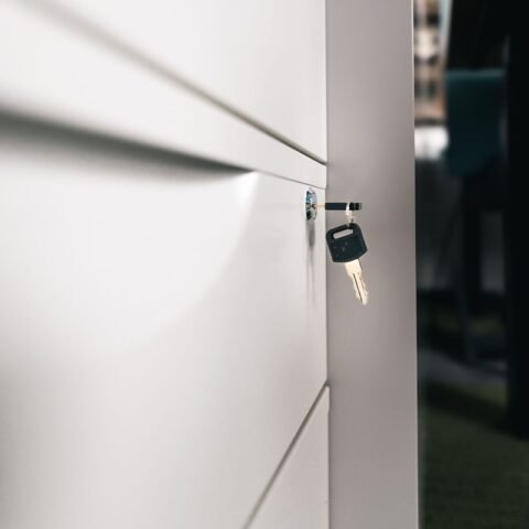 Clé sur une serrure d'un meuble blanc, bureau et chaise visibles
