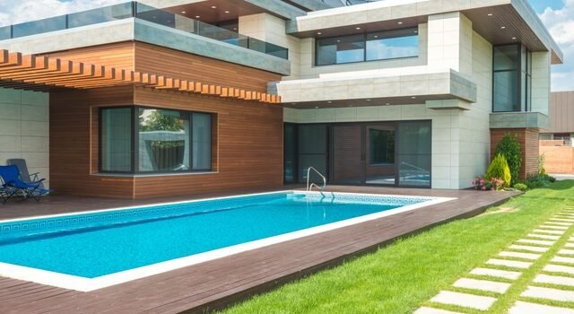 Piscine coque rectangulaire bleue installée dans le jardin d'une maison moderne à Bordeaux