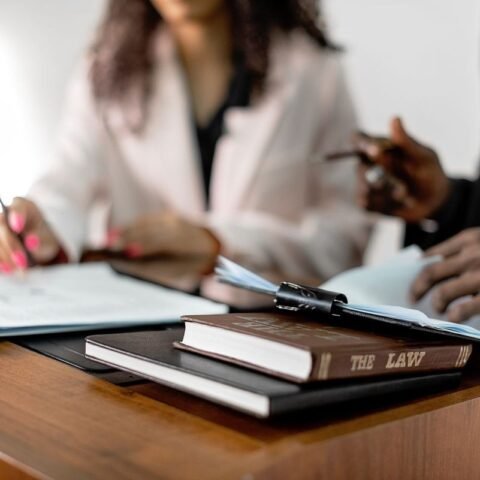 Deux individus signent des documents sur une table avec des livres et des dossiers