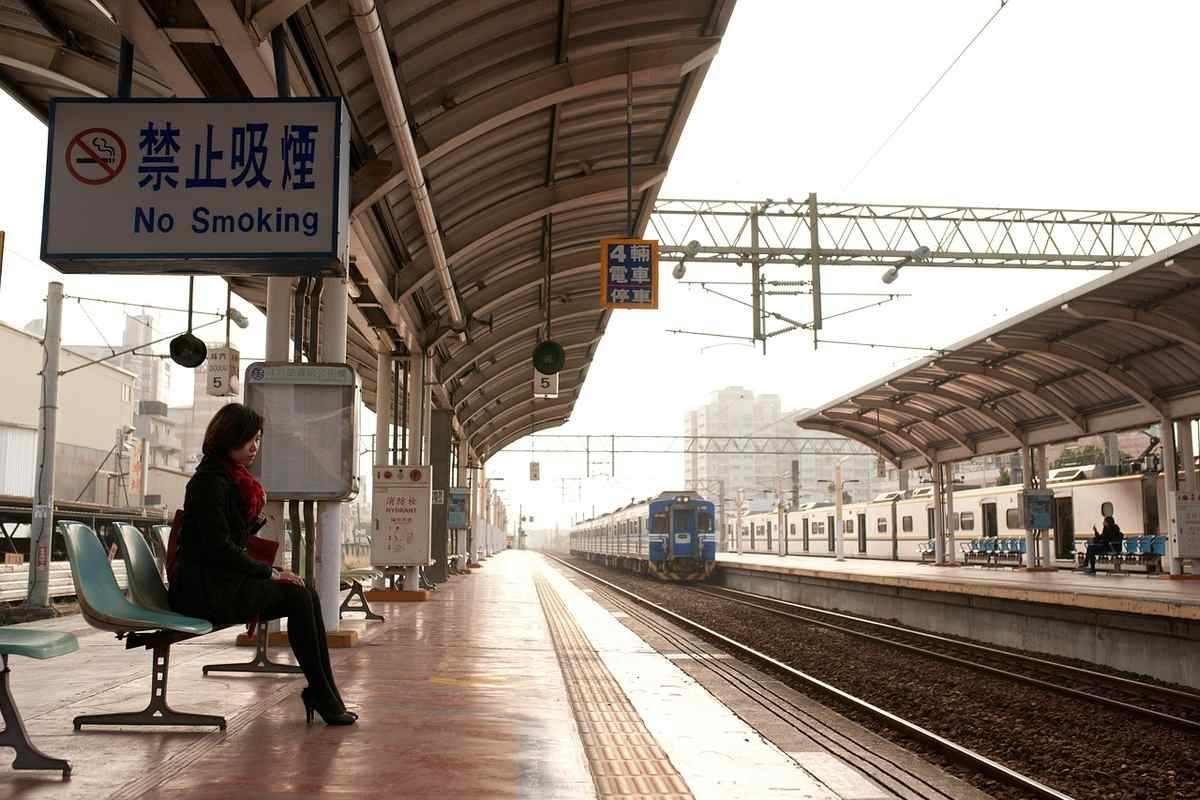 Une femme attend sur le quai de la gare, un train s'approche