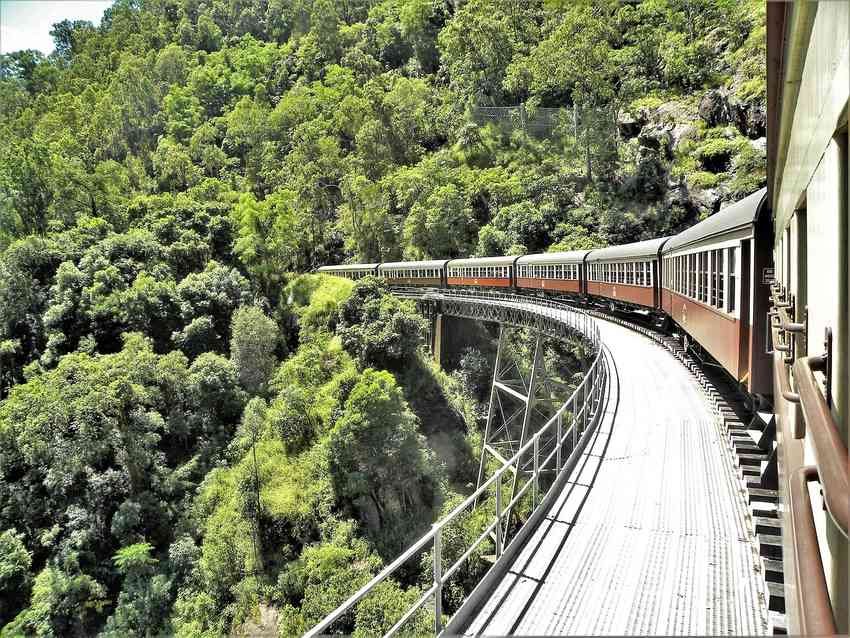 Un train rouge suit une voie courbe au-dessus d'une vallée verdoyante Un train rouge suit une voie courbe au-dessus d'une vallée verdoyante