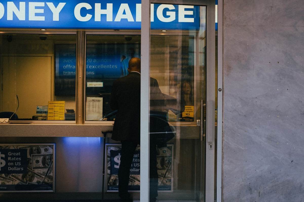 Un homme en costume se tient devant un comptoir de change d'argent