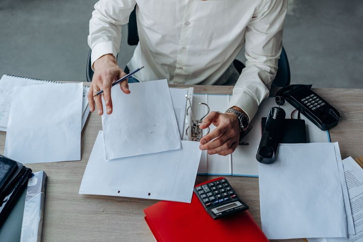 Un homme en chemise blanche examine des documents sur un bureau Un homme en chemise blanche examine des documents sur un bureau
